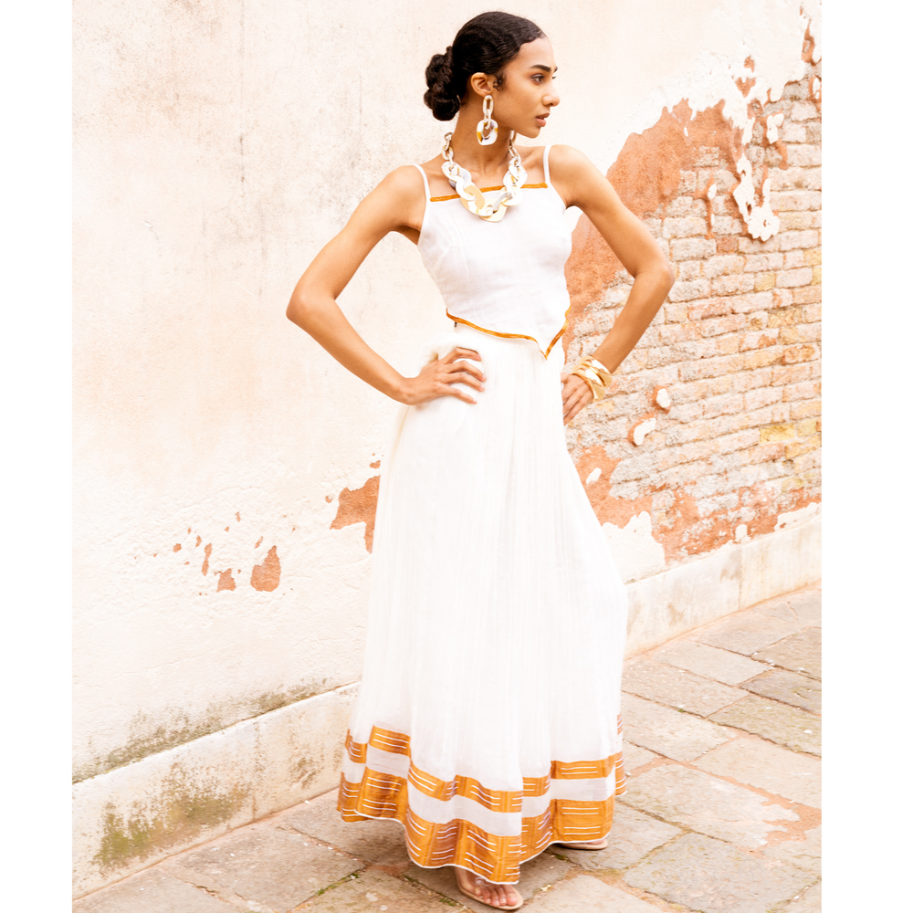 
                  
                     Discover the beauty of our 2-piece set: a handwoven maxi skirt and a hand-embroidered string top. Made from 100% Ethiopian cotton, each piece is unique and one-of-a-kind. The flowing fit of the maxi skirt suits any occasion, while the stylish string top is perfect for warm weather. Hand-embroidered details add stunning texture. Handmade for comfort and style, whether it's the beach or a formal event, this set is a perfect choice.
                  
                