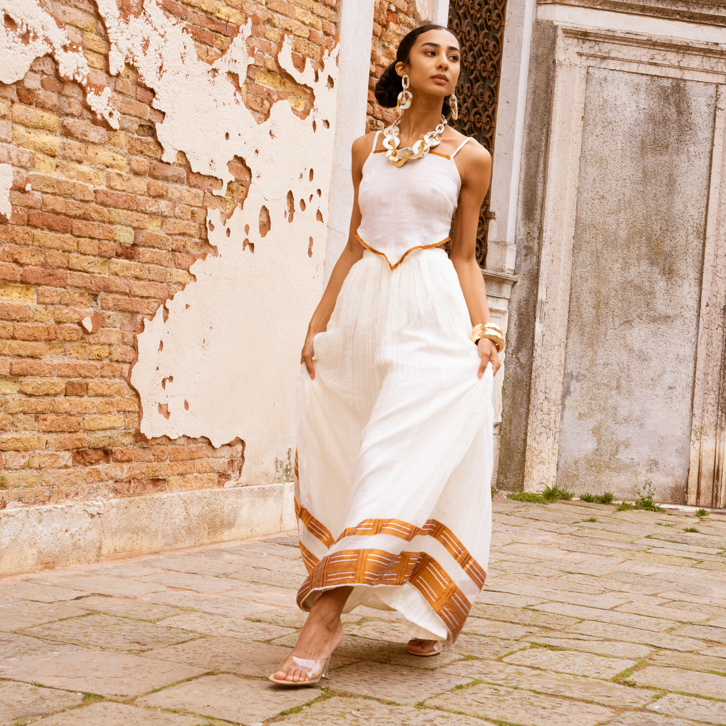  Discover the beauty of our 2-piece set: a handwoven maxi skirt and a hand-embroidered string top. Made from 100% Ethiopian cotton, each piece is unique and one-of-a-kind. The flowing fit of the maxi skirt suits any occasion, while the stylish string top is perfect for warm weather. Hand-embroidered details add stunning texture. Handmade for comfort and style, whether it's the beach or a formal event, this set is a perfect choice.